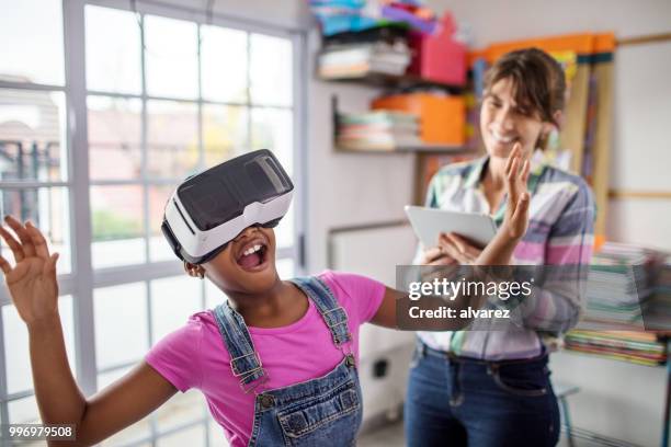 surprised schoolgirl wearing vr headset by teacher - virtual reality classroom stock pictures, royalty-free photos & images