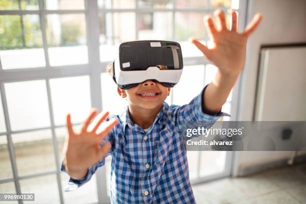 boy wearing vr headset while gesturing in class - vr kids stock pictures, royalty-free photos & images