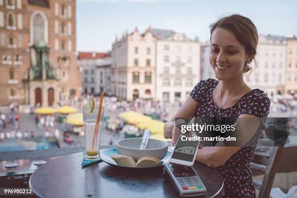 woman in krakow old town using digital wallet for mobile payment - malopolskie province stock pictures, royalty-free photos & images