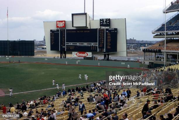 As baseball players warm up on the grass, spectators in the stands attend opening day at Shea Stadium, New York, New York, April 17, 1964. The day...