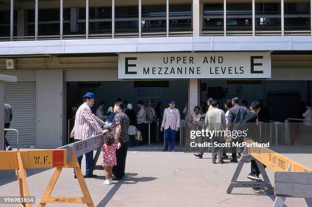 Ticket takers in red, white, and blue striped blazers, greet spectators as they enter Shea Stadium in Queens, New York, June 1, 1964.