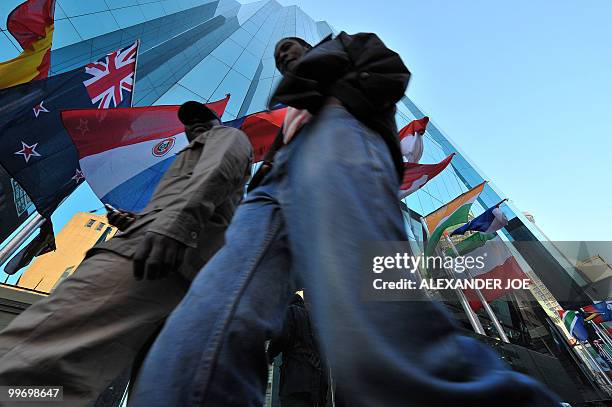 South Africans walking to work in Johannesburg on May 17, 2010 pass a building with the flags of the 32 countries that compete for Fifa World Cup...