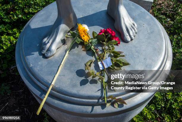 Flowers are laid at the feet of the statue of Ben Carlson, a Newport Beach lifeguard who died four years ago in big surf, on Friday, July 6, 2018 in...