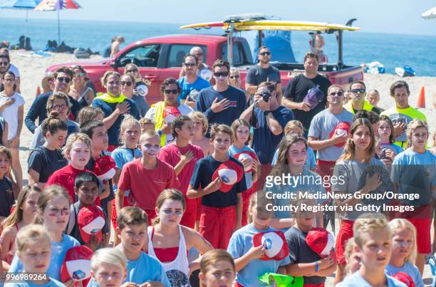 Hundreds stand as the national anthem is sung on Ben Carlson Day at the Junior Lifeguard Headquarters in Newport Beach on Friday, July 6, 2018....