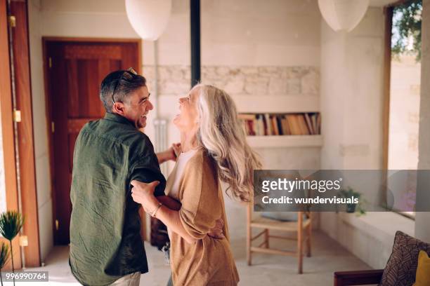 happy senior couple dancing and laughing together at home - listening imagens e fotografias de stock
