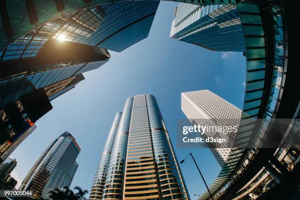 low angle view of contemporary corporate skyscrapers with well equipped infrastructures in busy financial district of hong kong against blue sky - infrastructures stock pictures, royalty-free photos & images