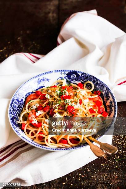 traditional italian food. bowl of homemade pasta spaghetti with fried shrimps or prawns, roasted red bell pepper, salted crumbled feta cheese, fresh dill on a wooden table, selective focus. - roasted pepper stock pictures, royalty-free photos & images