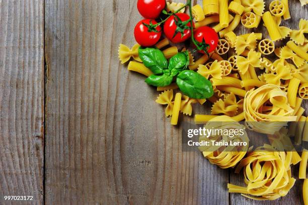 tomato basil and italian pasta rigatoni fettuccine penne farfalle on wooden background - tomato pasta stock pictures, royalty-free photos & images