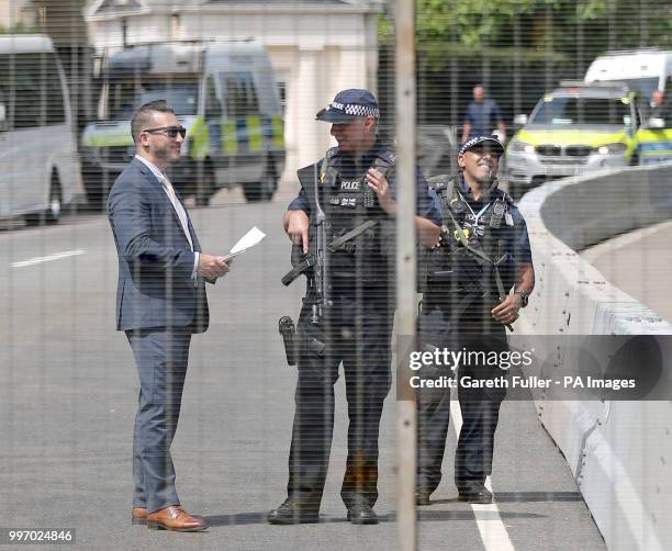 Armed police officers stand beyond a fence which is part of the security measures at Winfield House in London's Regents Park, where US President...