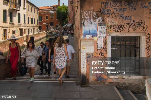 Tourists walk along the canal De La Toletta, where there are graffiti and tags on the walls, on the way that connects Accademia bridge to Railway...