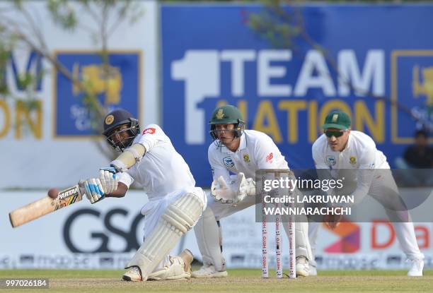 Sri Lankan cricketer Lakshan Sandakan plays a shot as South Africa's Quinton de Kock and Faf du Plessis look on during the first day of the opening...