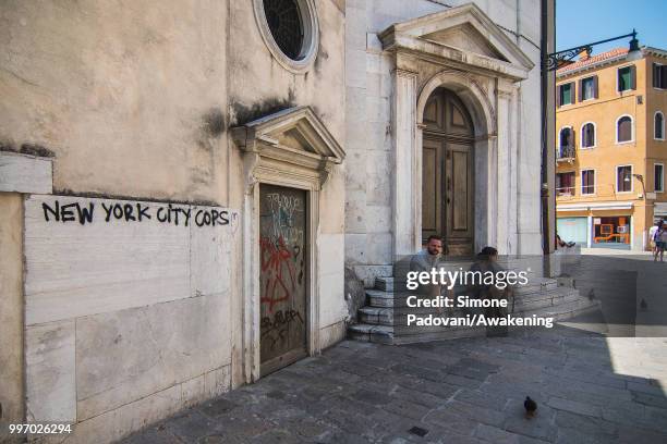 Tourists rest on the stairs of the church of Santa Maria Maddalena, where there are graffiti and tags on the walls, on the way that connects Railway...
