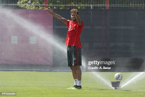 Javi Martinez of FC Bayern Muenchen jokes as the lawn sprinkler turns on during a training session at the club's Saebener Strasse training ground on...