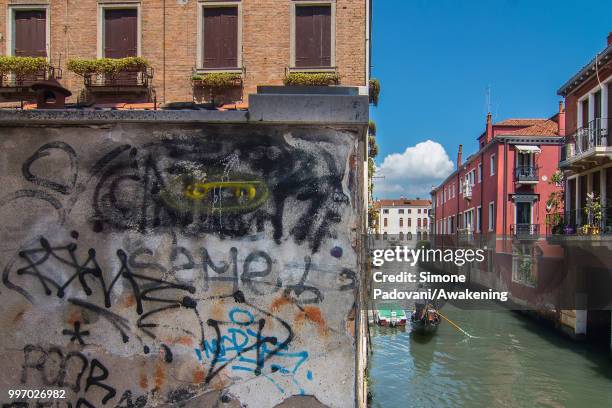 Gondola sails the canal of Marin, where there are tags and graffiti on the walls of the palaces, on the way that connect railway station to Rialto...