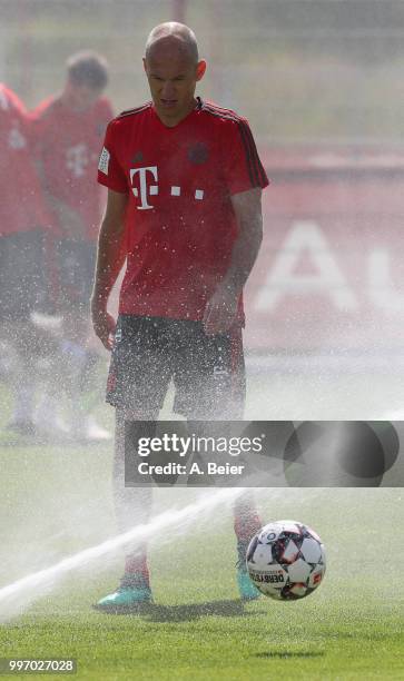 Arjen Robben of FC Bayern Muenchen is pictured as the lawn sprinkler turns on during a training session at the club's Saebener Strasse training...