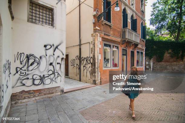 Tourist walks in Campiello di Arras, where there are graffiti and tags on the walls, through Dorsoduro district, on July 12, 2018 in Venice, Italy....