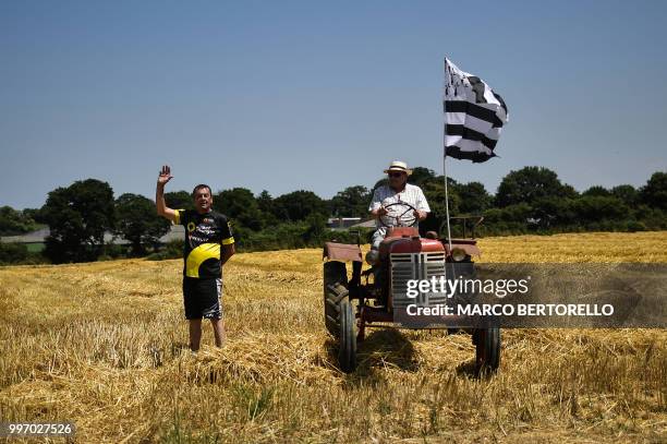 Spectator at the wheel of a tractor from which stands the flag of Brittany watches from a field during the sixth stage of the 105th edition of the...