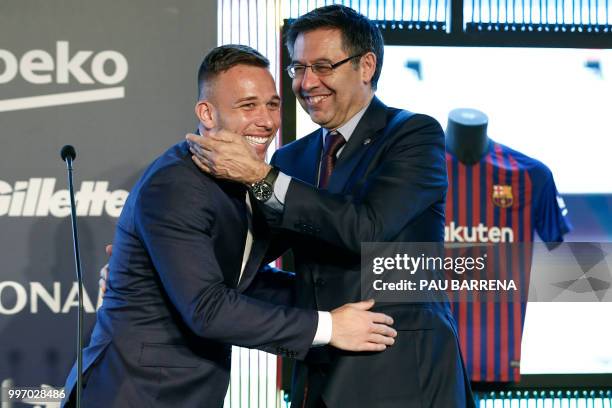 Barcelona's new player Brazilian midfielder Arthur Henrique Ramos de Oliveira Melo is hugged by Barcelona's president Josep Maria Bartomeu during his...