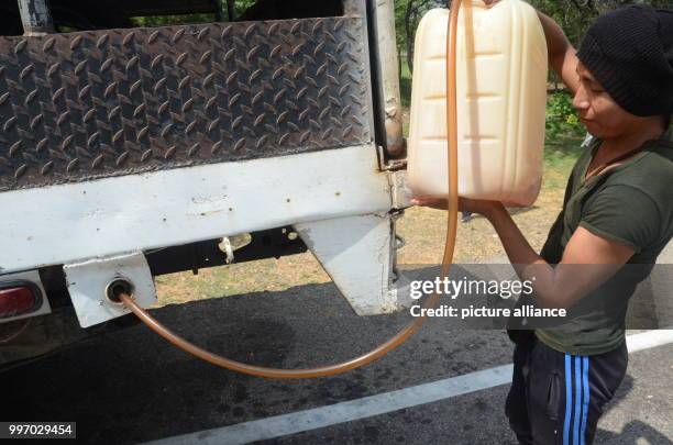 Franklin López of the Wayuu indigenous tribe fills the tank of his vehicle with smuggled petrol in Maicao, Colombia, 5 September 2017. There are...