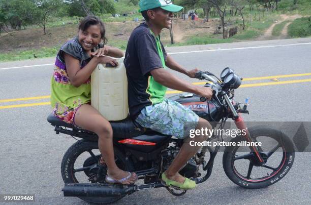 Young couple of the Wayuu indigenous tribe can be seen on their motorcycle transporting a canister of petrol in Maicao, Colombia, 5 September 2017....