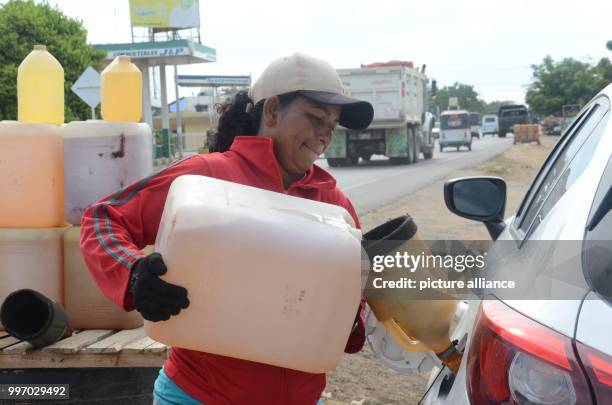 Woman of the Wayuu indigenous tribe fills the tank of her car with petrol smuggled across the broder from Venezuela, in Maicao, Colombia, 5 September...