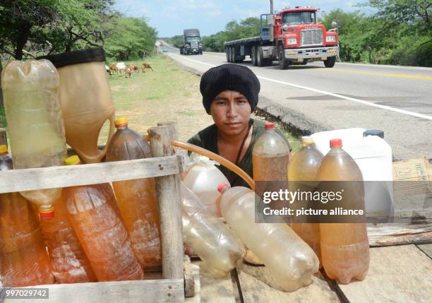 Franklin López of the indigenous Wayuu tribe sits with his smuggled petrol which is on sale in Maicao, Colombia, 5 September 2017. Many in the region...
