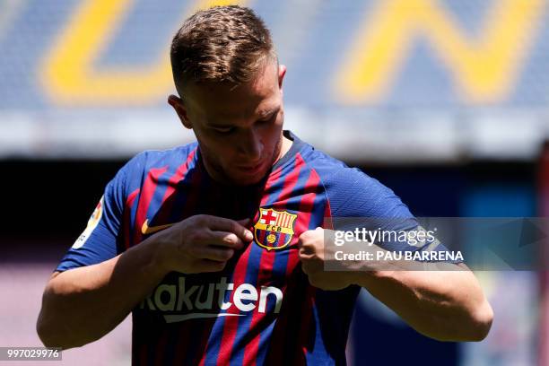 Barcelona's new player Brazilian midfielder Arthur Henrique Ramos de Oliveira Melo looks at his new jersey during his official presentation at the...