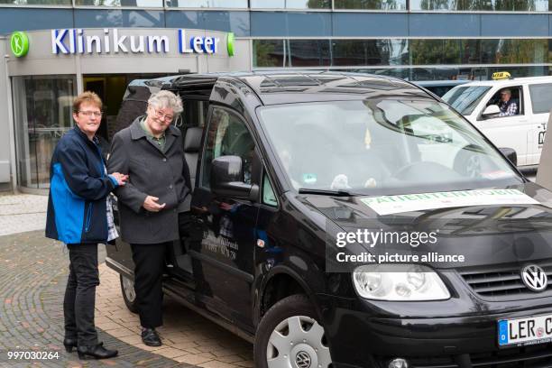 Taxi driver Mrs. Hilbrands helping the patient, Mrs. Busenga, to board the patient mobile in front of the Leer Clinic in Leer, Germany, 04 October...