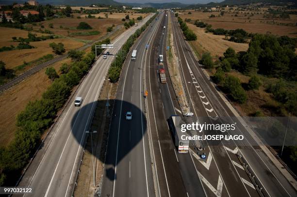 The shadow of a hot-air balloon is pictured over a highway during the 22th European Balloon Festival in Igualada, near Barcelona on July 12, 2018. -...