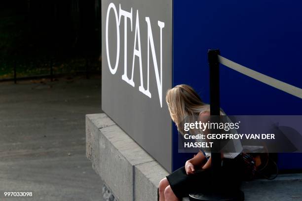 Woman sits beside a NATO sign at a working dinner at The Parc du Cinquantenaire - Jubelpark Park in Brussels on July 11 during the North Atlantic...