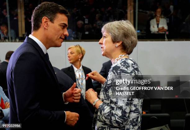 Spain's Prime Minister Pedro Sanchez and Britain's Prime Minister Theresa May talk on the second day of the NATO summit, in Brussels, on July 12,...