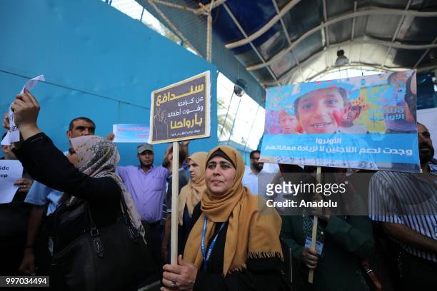 The United Nations Relief and Works Agency for Palestine Refugees in the Near East staff hold banners during a protest as they demand the protection...