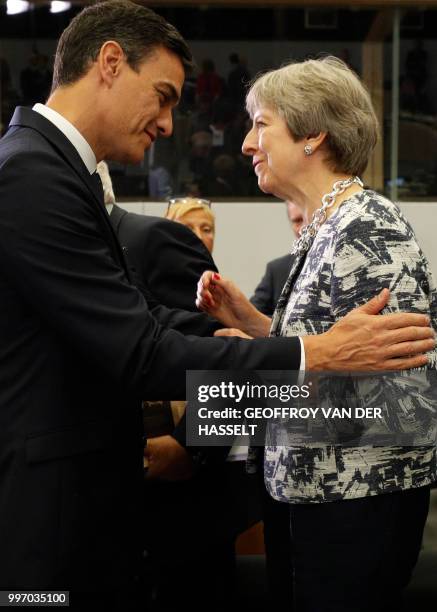 Spain's Prime Minister Pedro Sanchez and Britain's Prime Minister Theresa May talk on the second day of the NATO summit, in Brussels, on July 12,...