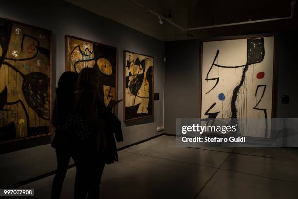 People in the shadows look at the paintings during on exhibition of famous painter Joan Mirò at the Palazzo Chiablese.