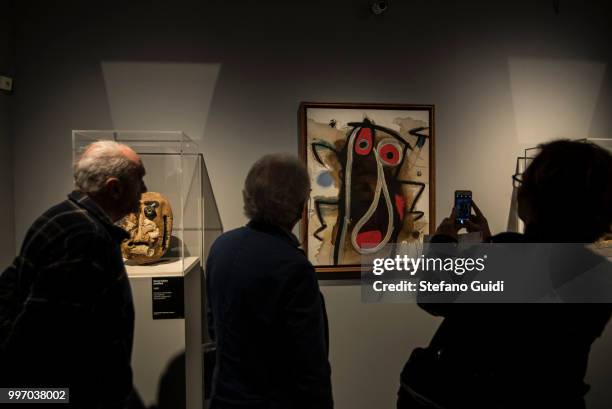 People in the shadows look at the paintings during on exhibition of famous painter Joan Mirò at the Palazzo Chiablese.