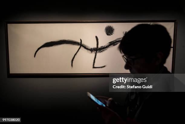 Woman photographs a painting in the shadows during on exhibition of famous painter Joan Mirò at the Palazzo Chiablese.