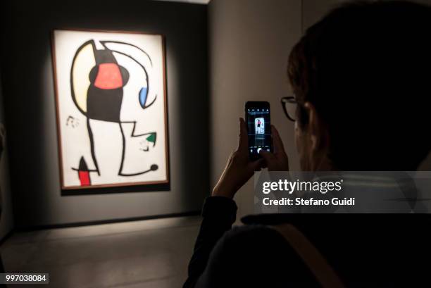 Woman photographs a painting in the shadows during on exhibition of famous painter Joan Mirò at the Palazzo Chiablese.