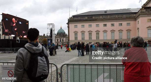 Visitors who failed to gain admission to a free concert in the State Opera watch the concert on a screen outside the building in Berlin, Germany, 7...