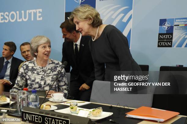 S US Ambassador Kay Bailey Hutchison speaks with Britain's Prime Minister Theresa May during a meeting on the second day of the North Atlantic Treaty...