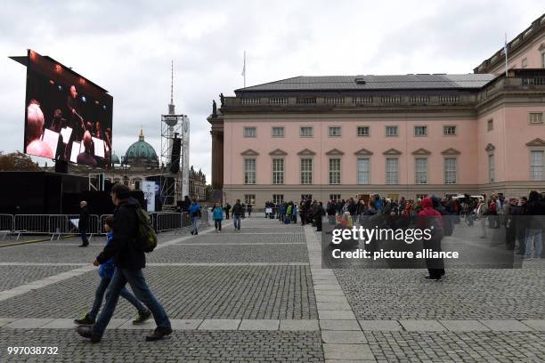 Visitors who failed to gain admission to a free concert in the State Opera watch the concert on a screen outside the building in Berlin, Germany, 7...