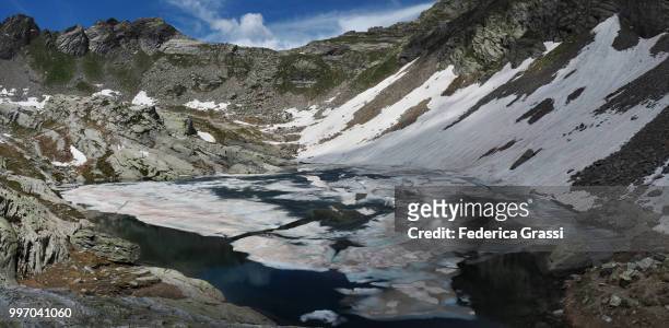 panoramic of partly frozen upper paione lake (lago del paione superiore), bognanco valley - lepontinische alpen stock-fotos und bilder