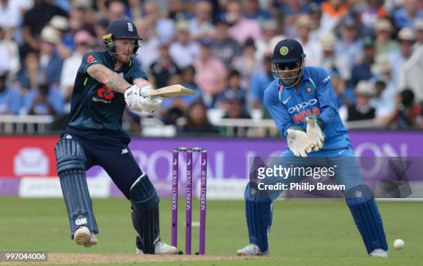 Ben Stokes of England hits out watched by MS Dhoni of India during the 1st Royal London One-Day International between England and India on July 12,...