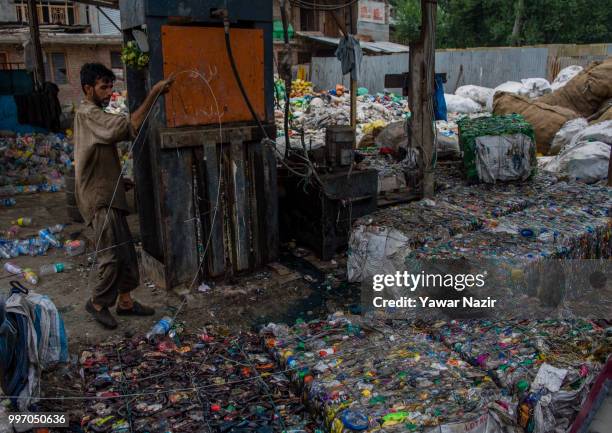 Kashmiri laborer ties compresses plastic bottles, at a recycling center on July 12, 2018 in Srinagar, the summer capital of Indian administered...