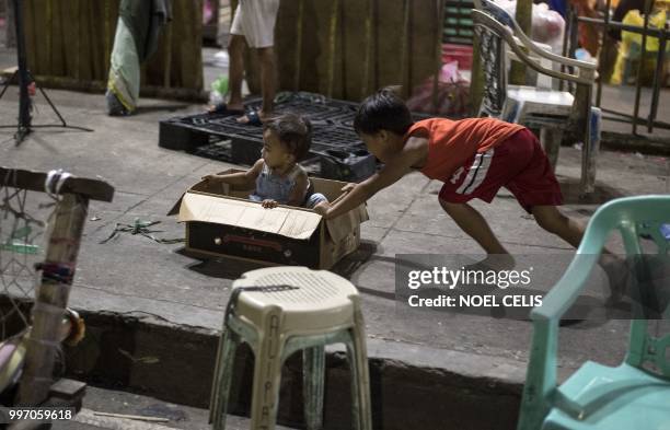 Children play with a cardboard box at Divisoria Market in Manila on July 12, 2018.
