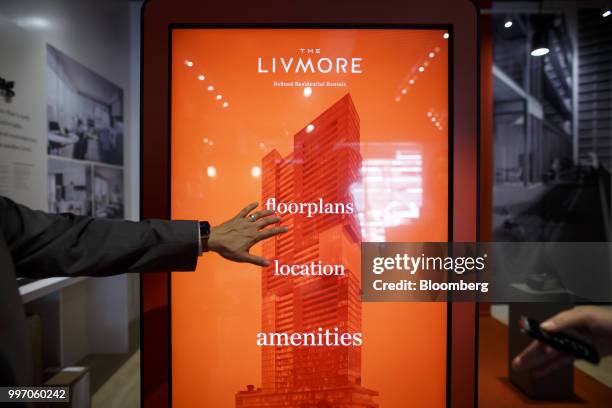 Sales associate points to a screen displaying information about the GWL Realty Advisors Livmore luxury apartment building in Toronto, Ontario,...
