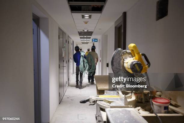 Workers carry equipment during construction of the GWL Realty Advisors Livmore luxury apartment building in Toronto, Ontario, Canada, on Tuesday,...