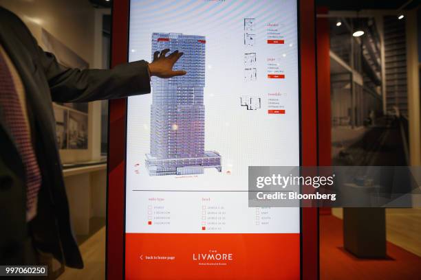 Sales associate points to a screen displaying a rendering of the GWL Realty Advisors Livmore luxury apartment building in Toronto, Ontario, Canada,...