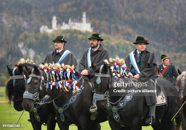 Men and women in traditional dress ride on festively adorned horses from the St. Coloman church near Schwangau, Germany, 8 October 2017. They are...
