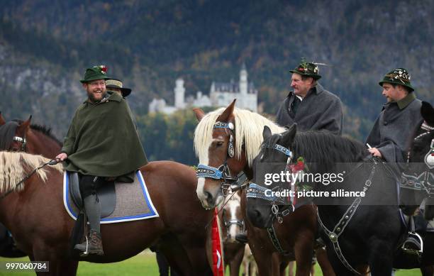 Men and women in traditional dress ride on festively adorned horses from the St. Coloman church near Schwangau, Germany, 8 October 2017. They are...