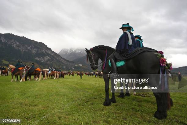 Men and women in traditional dress ride on festively adorned horses from the St. Coloman church near Schwangau, Germany, 8 October 2017. They are...